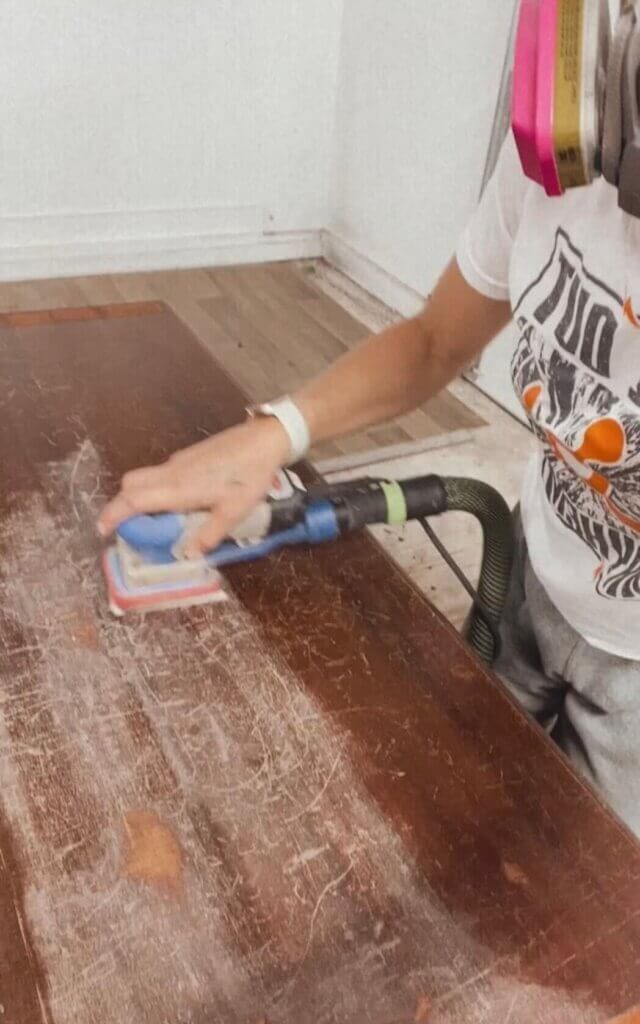 Preparing a piece of furniture for paint by scuff sanding.