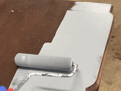 photo of rolling a gray primer onto the top of a piece of furniture