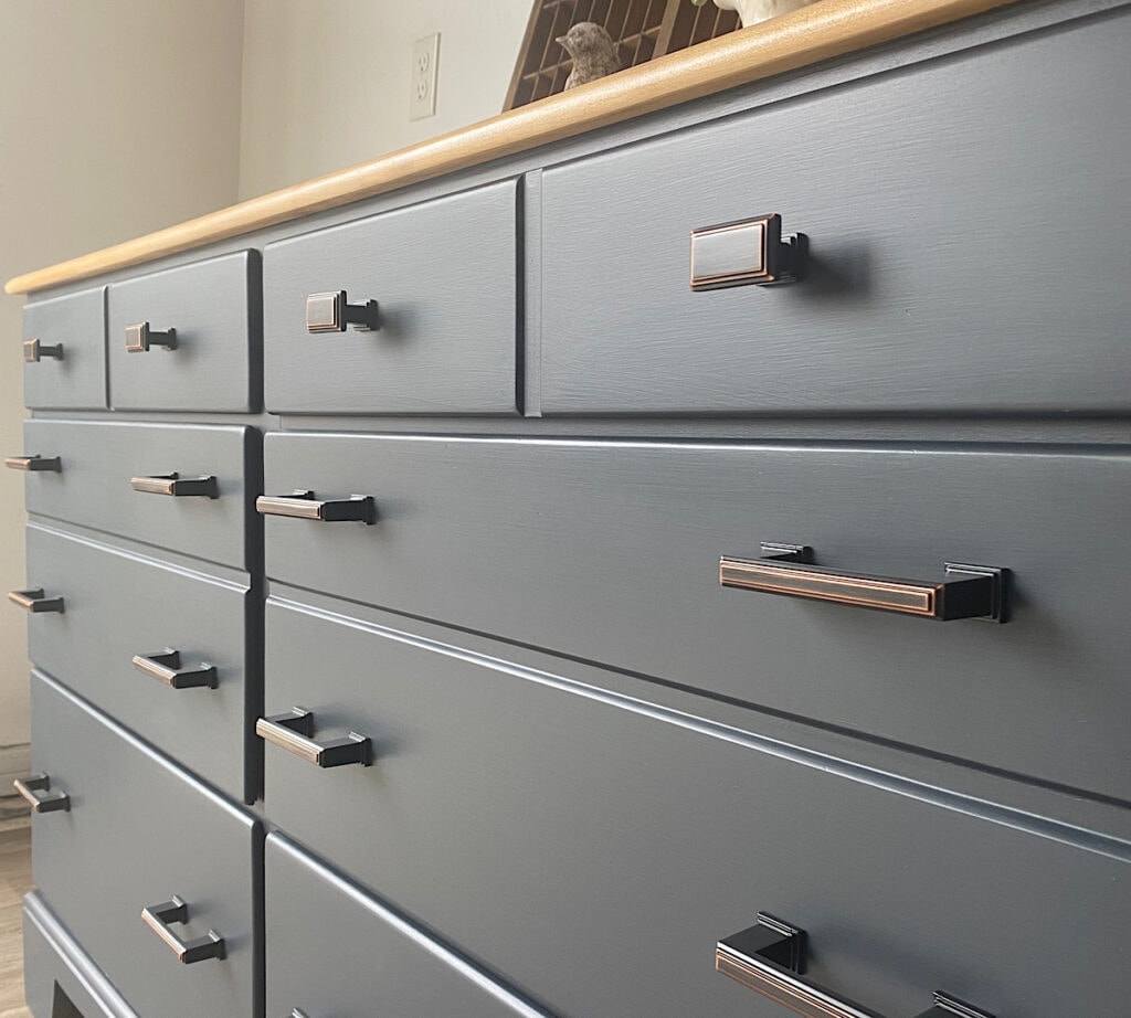 Angled closeup photo of a navy blue painted dresser with oil rubbed bronze hardware pulls.