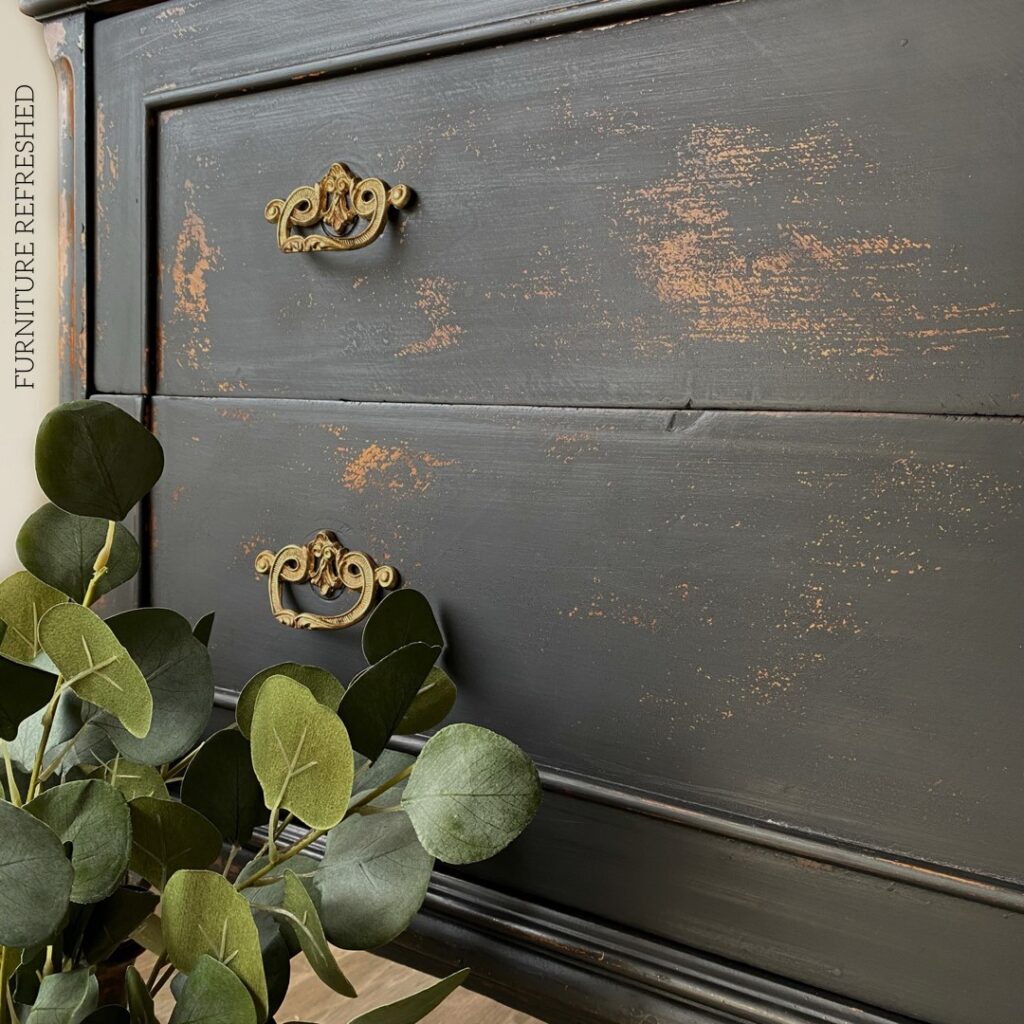 Closeup photo of antique dresser with a black chippy paint finish.