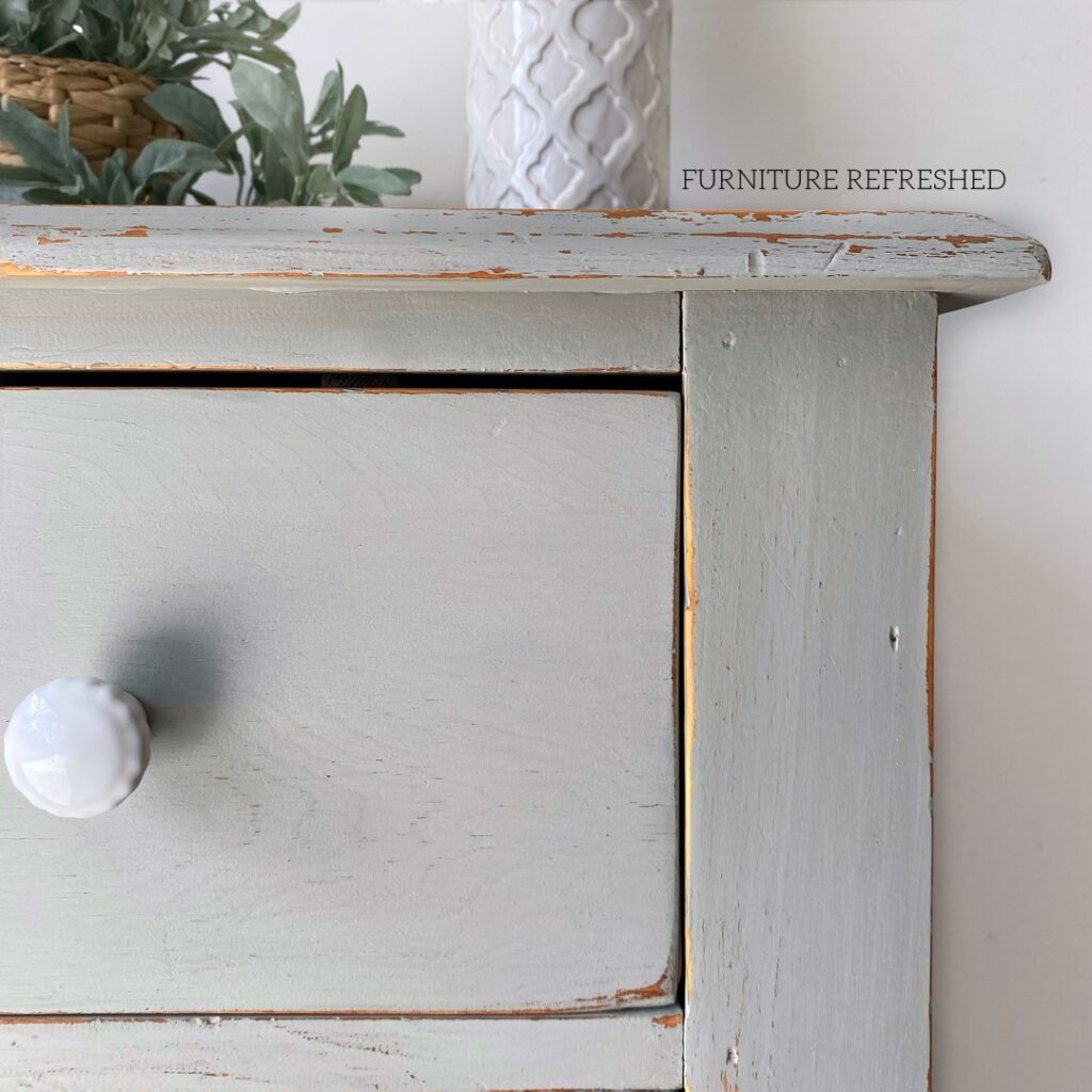 Closeup photo of antique dresser with a light blue chippy paint finish.