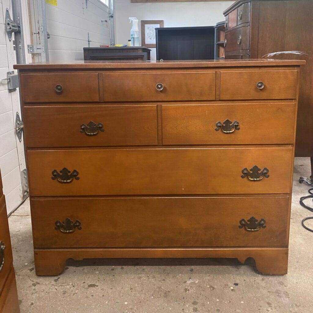 Photo of a vintage Ethan Allen maple 4 drawer dresser with knobs on the top drawer and chippendale hardware on the bottom 3 drawers.