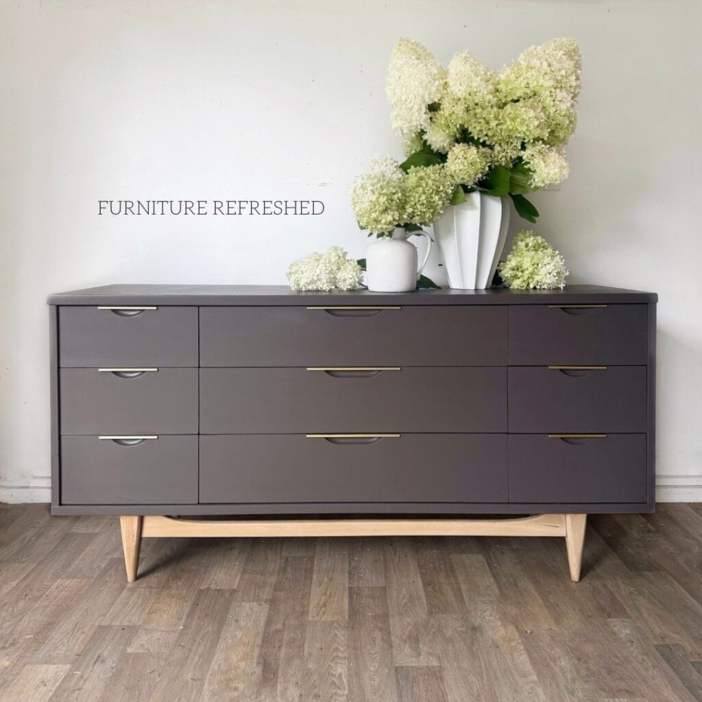 Front view 9 drawer mcm dresser painted in a smoky brown with a light wood base and brass pulls.