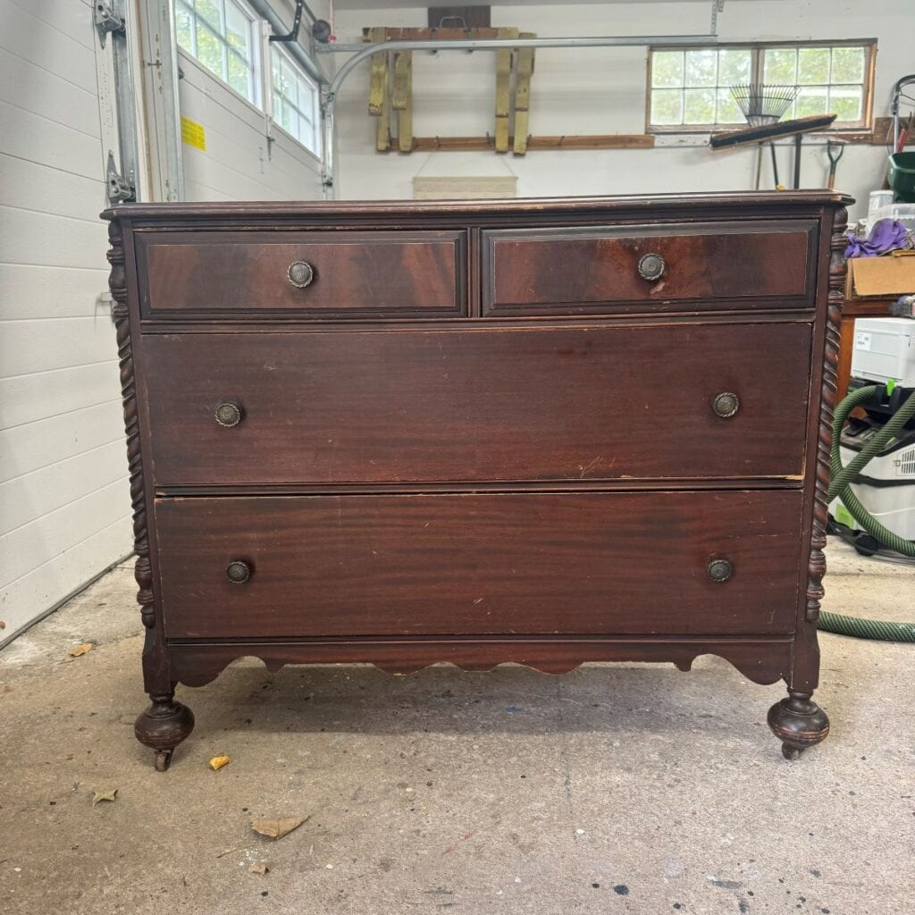 Before photo of the dresser used in the makeover. It has 4 drawers and bun feet.  It is stained dark brown.