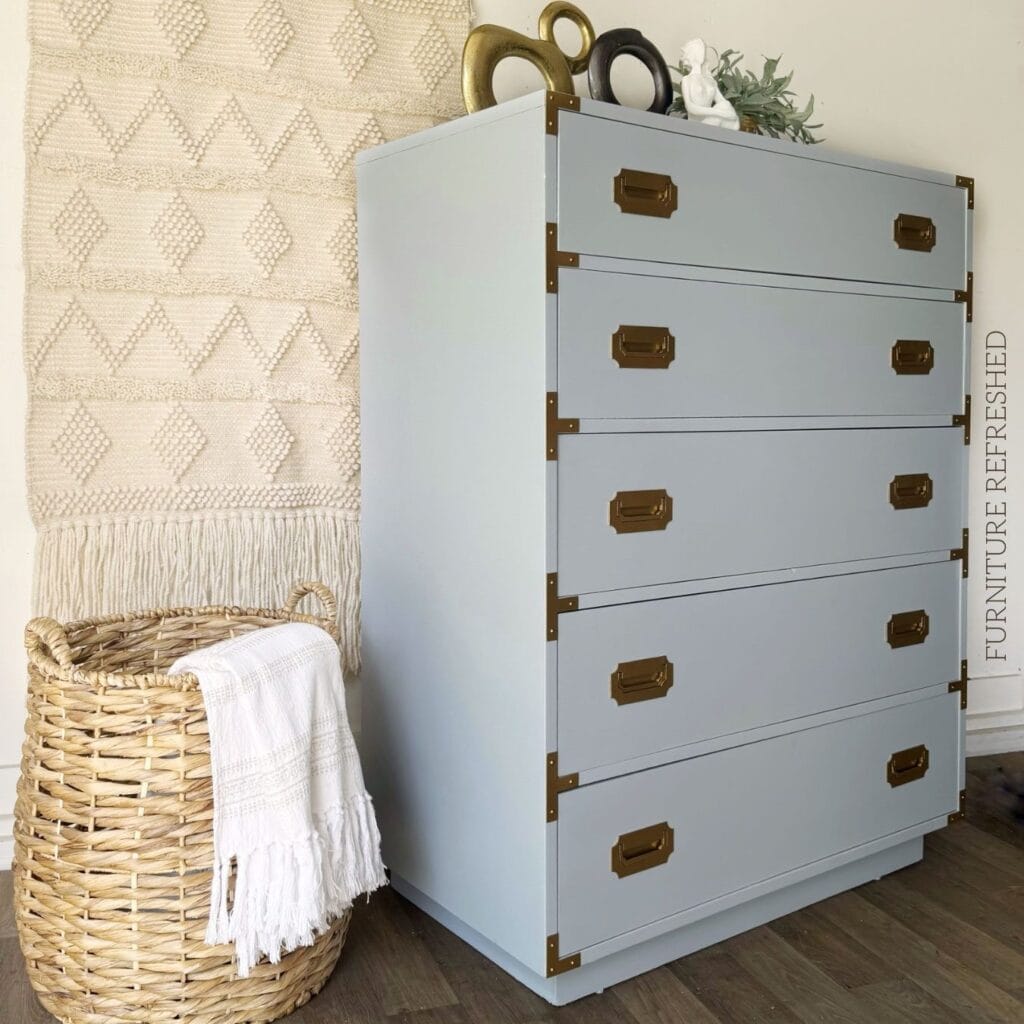 After photo of the 5 drawer dresser used in this makeover. Side view. It is a Dixie Furniture Campaigner style, painted light blue with gold hardware.