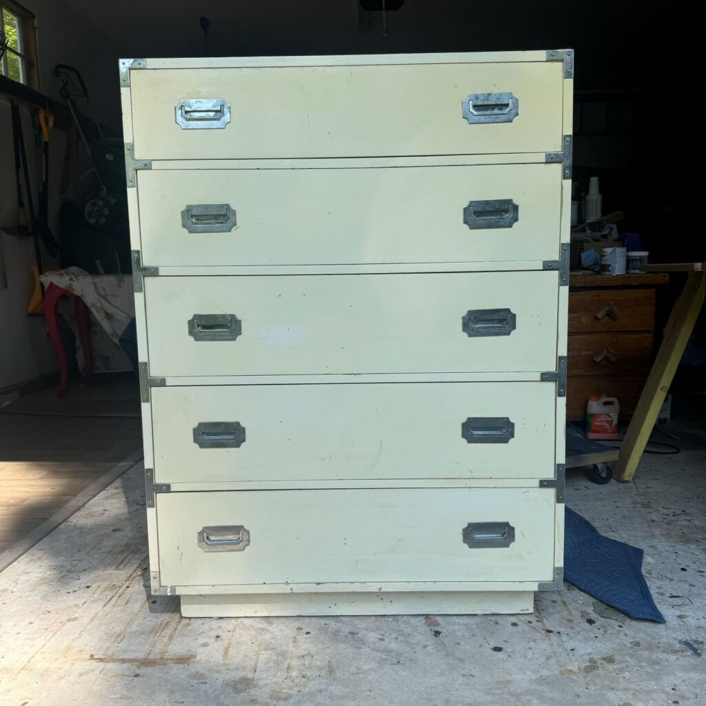 Before photo of the 5 drawer dresser used in this makeover. It is a Dixie Furniture Campaigner style, painted white with chrome hardware.