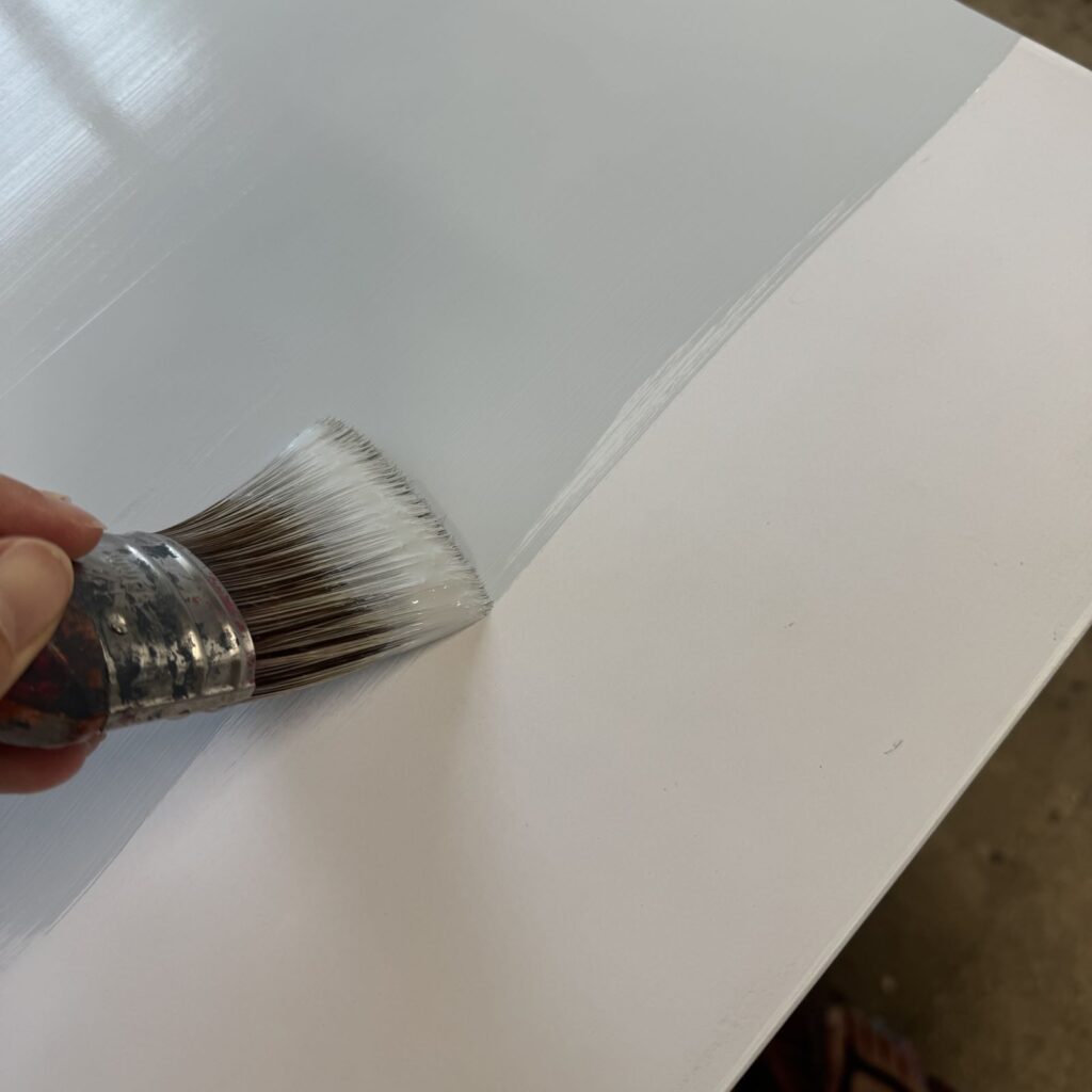 Applying paint to the laminate top of this dresser.