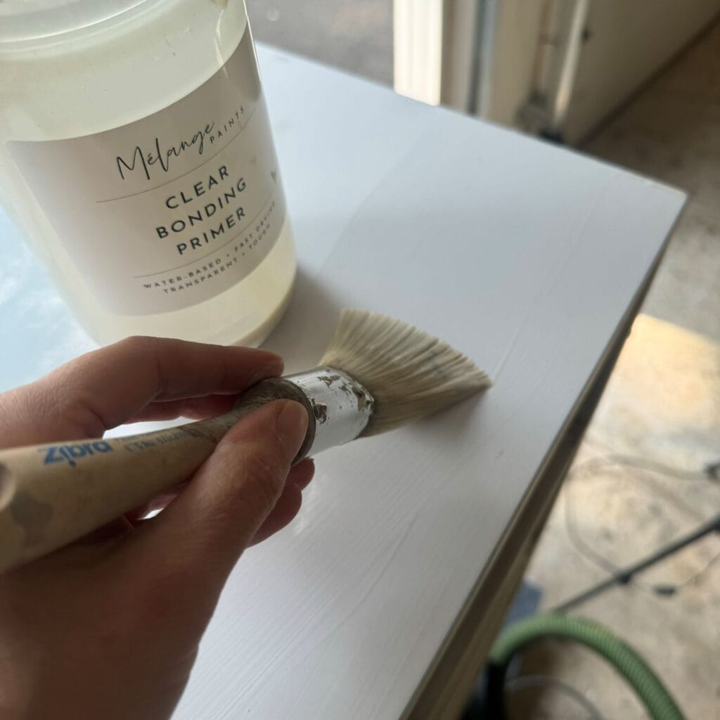 Applying clear bonding primer to the top of this laminate dresser.