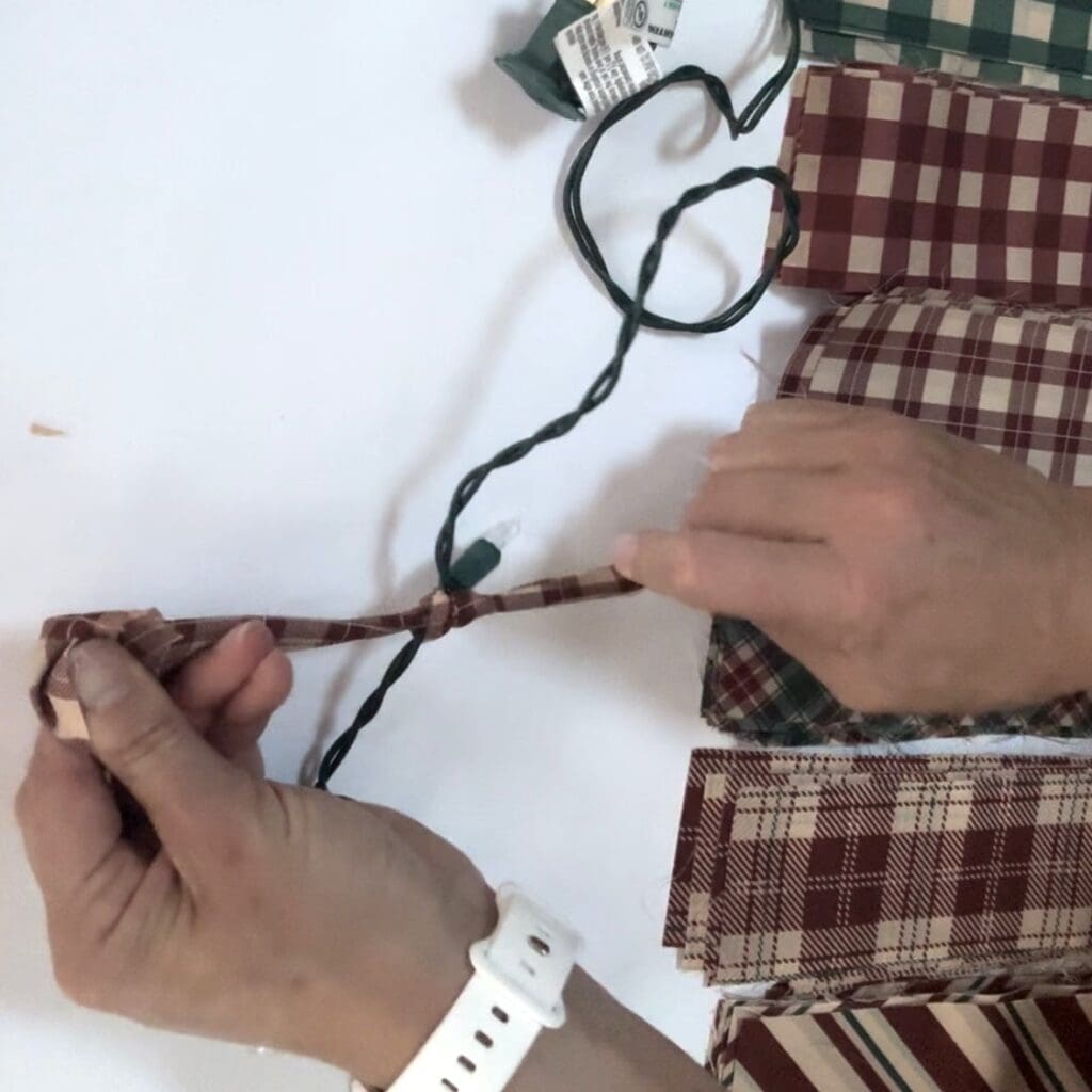 Tying a piece of fabric onto the string of lights.