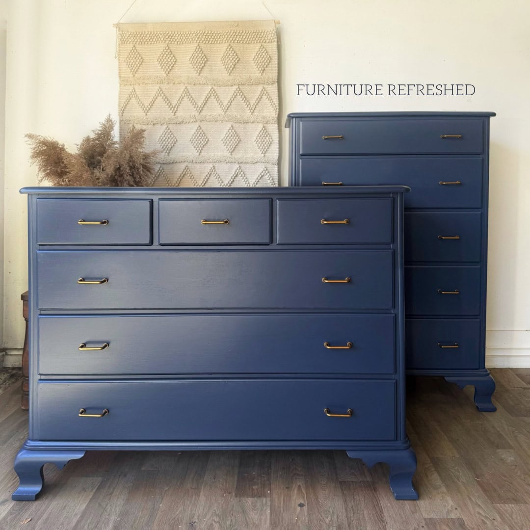 Photo of both dressers completed in the makeover, with navy paint and new aged brass hardware.