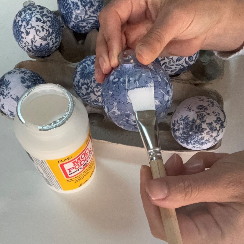 Applying Mod Podge to seal the Chinoiserie Christmas ornament.