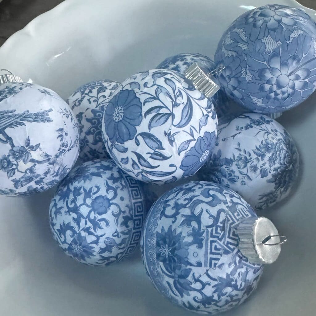 Eight Chinoiserie Christmas ornaments displayed in a white bowl.