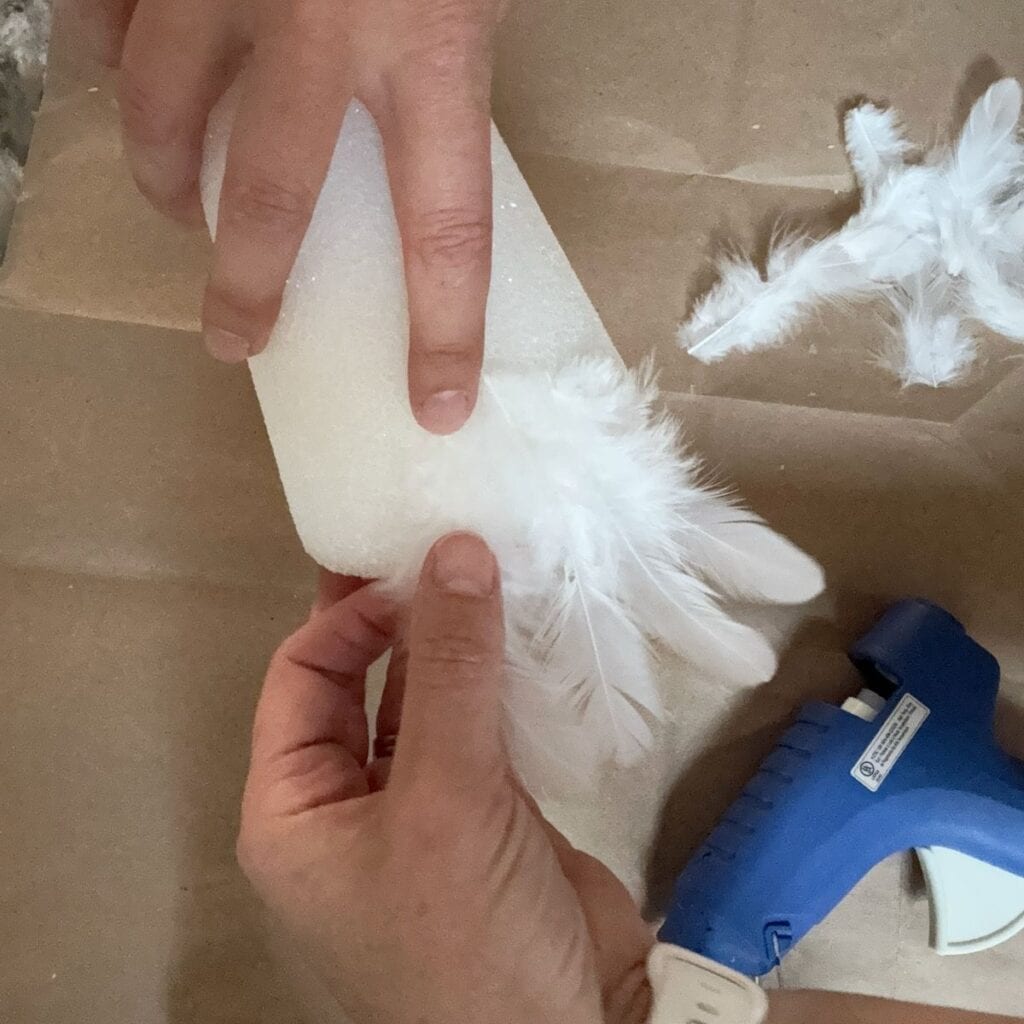 GLuing feathers to the base of the cone.