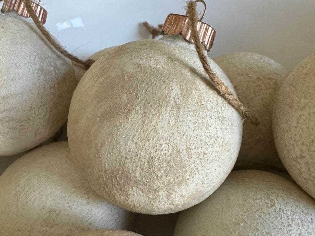 Close up of white textured Christmas ornament with a aged gold top and brown twine.