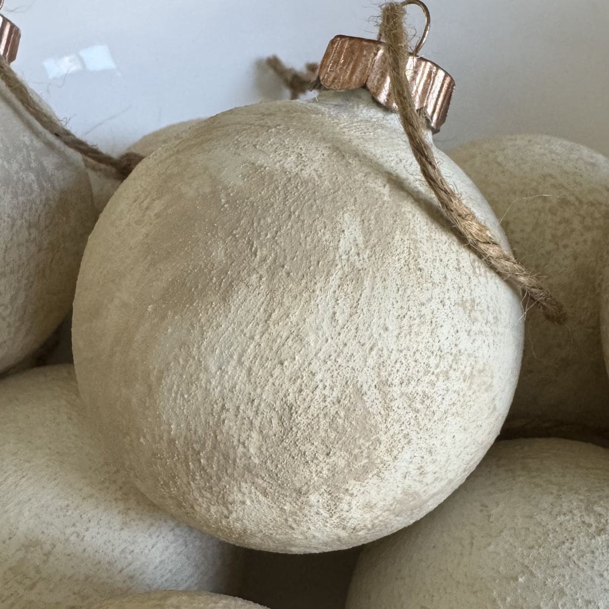 Close up of white textured Christmas ornament with a aged gold top and brown twine.