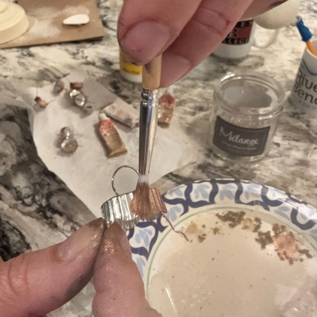 Applying rub n buff to the metal ornament tops with an artists brush.