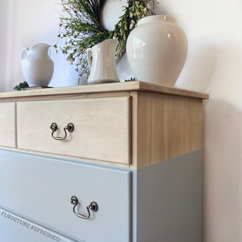 Close up side angle of the top portion of a dipped dresser. The top is wood and the lower painted potion is light blue.