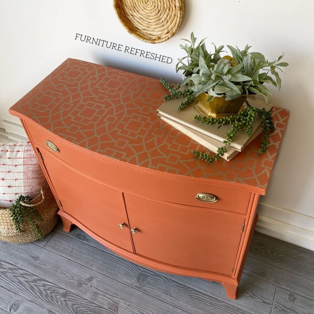 Photo of a painted orange sideboard with a gold stencil pattern on top.