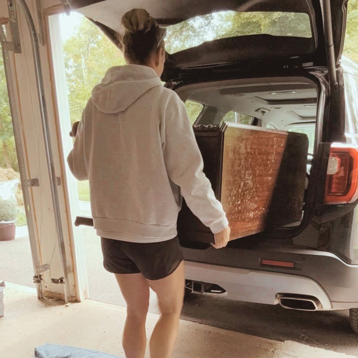 Unloading a dresser to be flipped from an SUV into a garage.