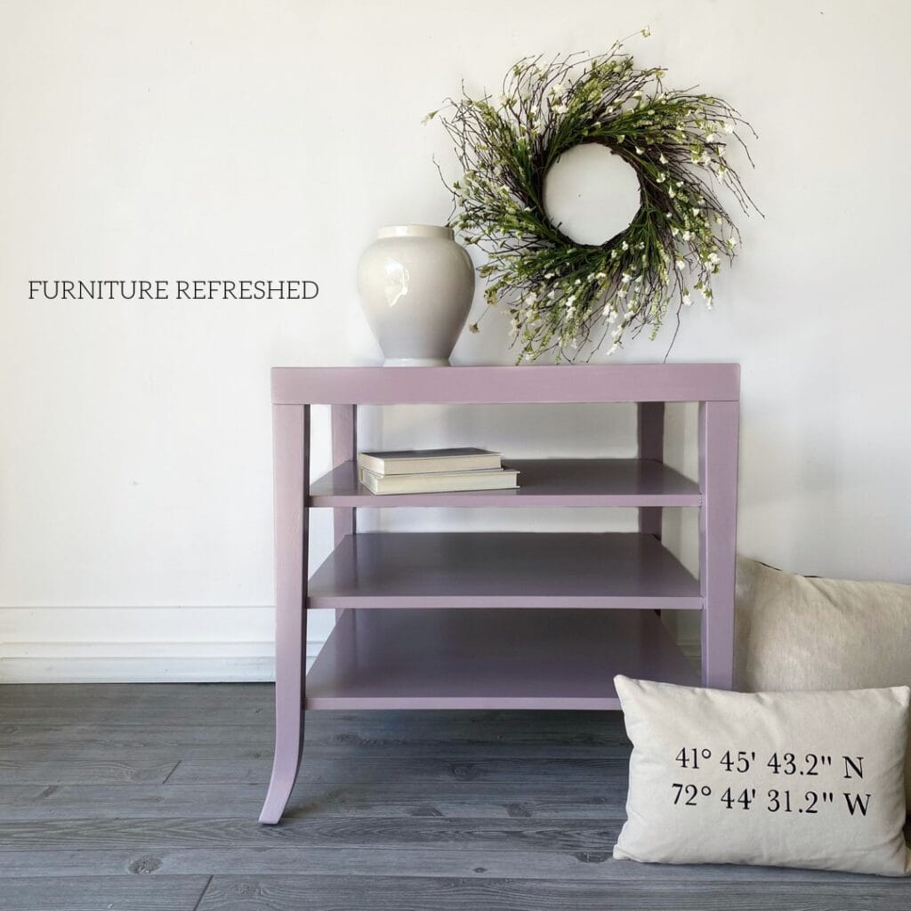 Photo of a lavender side table staged with a vase, pillow and wreath.