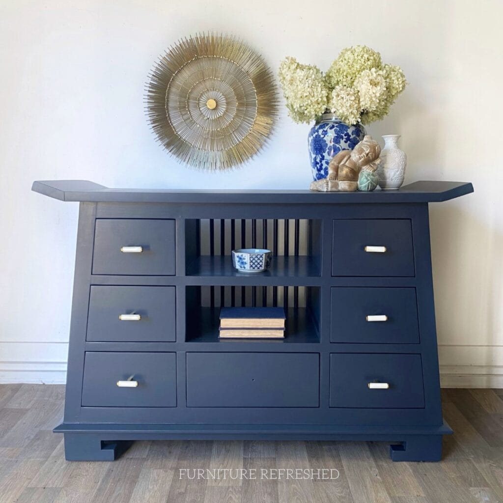 After photo of Chinoiserie style sideboard painted dark blue with white marble knobs.