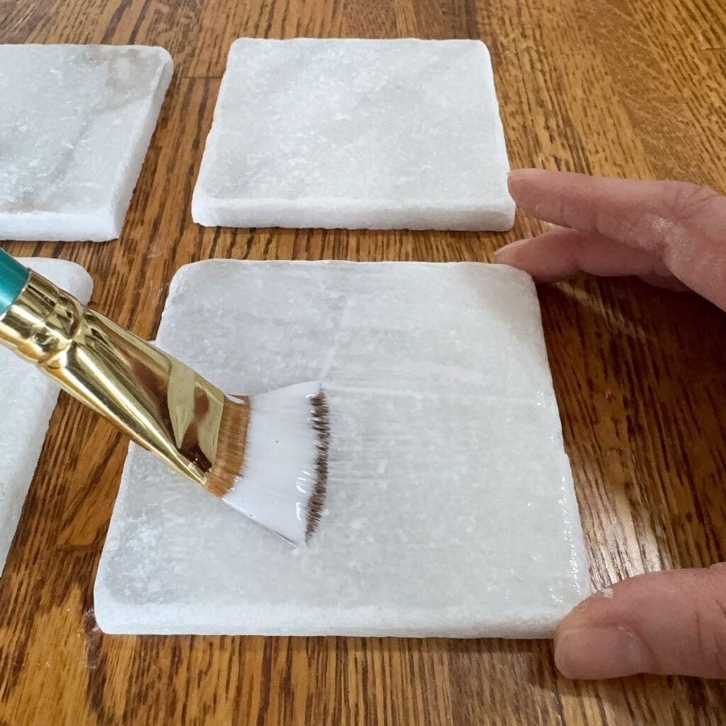 Applying mod podge to the plain tile.