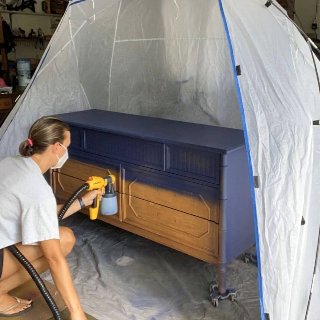 Painting a dresser blue using a Wagner spray gun.